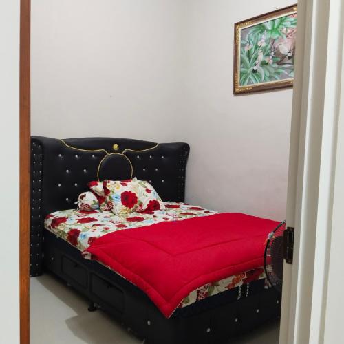 um quarto com uma cama com um cobertor vermelho em Villa keluarga sejahtera em Batu