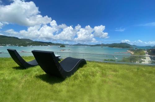 a pair of chairs sitting in the grass overlooking a lake at WM Hotel Hong Kong, Vignette Collection in Hong Kong
