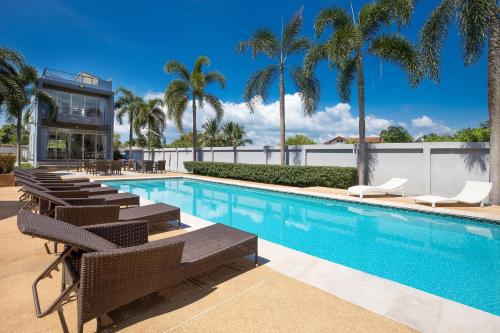 a swimming pool with lounge chairs and palm trees at Pool Access Villa Argent 8, 3-Bedroom near Mission Hills Golf in Thalang