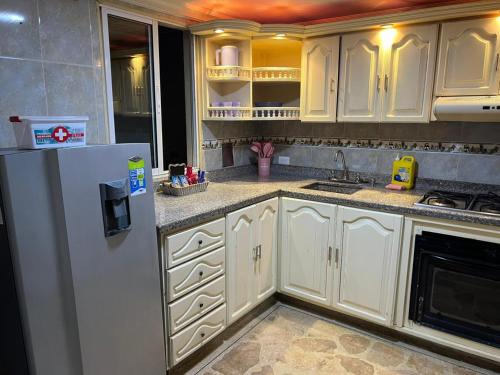 eine Küche mit weißen Schränken und einem Kühlschrank in der Unterkunft Acogedor espacio cerca del Metro in Bello