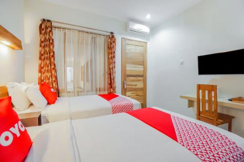 a hotel room with two beds and a flat screen tv at OYO 90319 Angler Guest House Malang in Malang