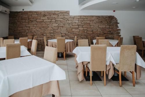 una sala da pranzo con tavoli, sedie e un muro di mattoni di Verslo Klasė-easy to stay a Panevėžys