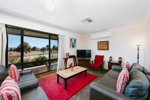 a living room with a couch and a table at Ithaca Farm Cottage - Country View Seclusion in Mudgee