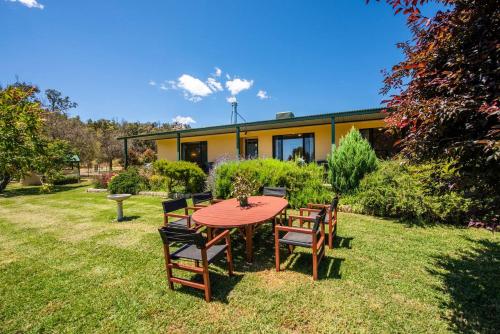 a table and chairs in front of a house at Ithaca Farm Cottage - Country View Seclusion in Mudgee
