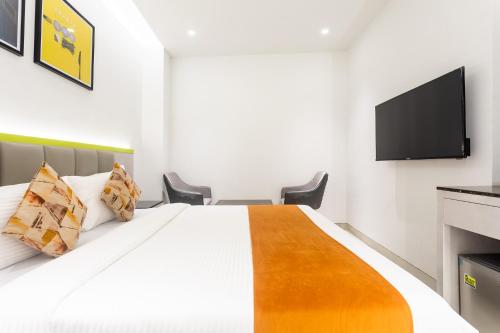 a bedroom with a bed and a flat screen tv at FabHotel Prime Oasis Orange in Bhopal