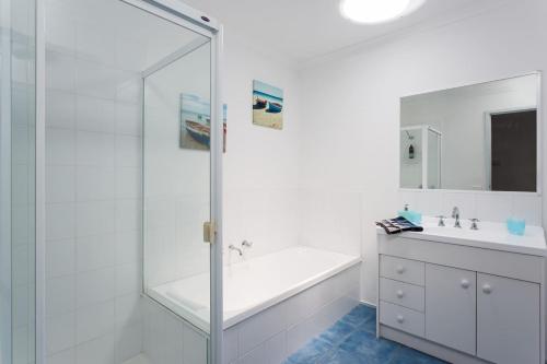 a white bathroom with a tub and a sink at Stroll to the Sea - Sun-drenched Seaside Lifestyle in Rye