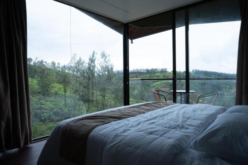 a bedroom with a bed in front of a large window at OOTYHOMZ LUXURY STAY in Ooty