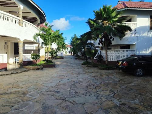 a street in front of a building with palm trees at Kimbi's Villa in Ukunda