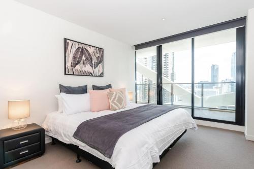 een slaapkamer met een bed en een groot raam bij City Road Sanctuary with Sunset Views & Parking in Melbourne