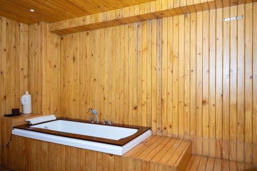 uma banheira numa casa de banho com painéis de madeira em Hotel Global em Bhatha