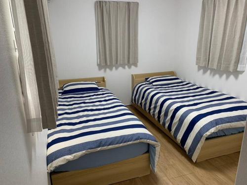 two beds sitting next to each other in a room at 藤沢HOME-1f in Fujisawa