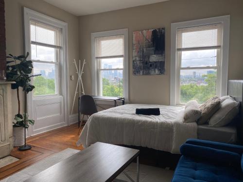 a bedroom with a bed and a couch and windows at Cozy apartment with city skyline. Easy commute midtown Manhattan. in Jersey City