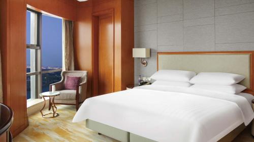 a bedroom with a large white bed and a chair at InterContinental Changzhou by IHG in Changzhou