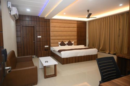 um quarto com uma cama, uma cadeira e um sofá em Atithi Regency em Dhuburi