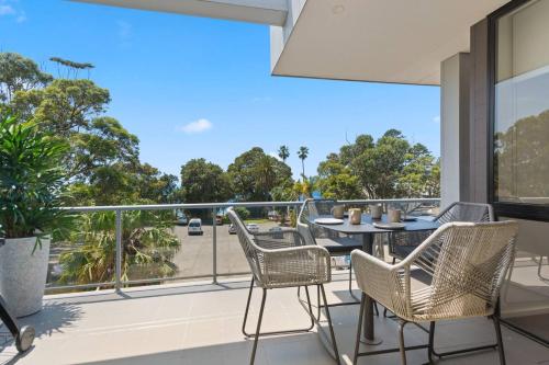 a patio with a table and chairs on a balcony at Addison's Escape - A Breezy Beachfront Beauty in Shellharbour