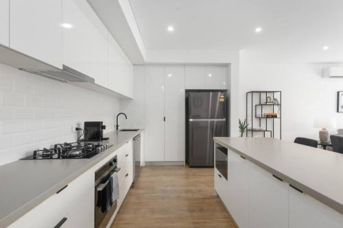 a kitchen with white counters and a stainless steel refrigerator at Addison's Escape - A Breezy Beachfront Beauty in Shellharbour