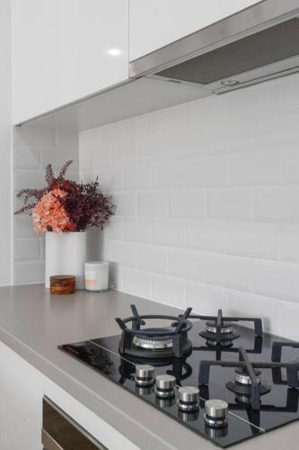 a kitchen with a stove top with a vase of flowers at Addison's Escape - A Breezy Beachfront Beauty in Shellharbour