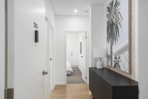 a white hallway with a black dresser and a bedroom at Addison's Escape - A Breezy Beachfront Beauty in Shellharbour
