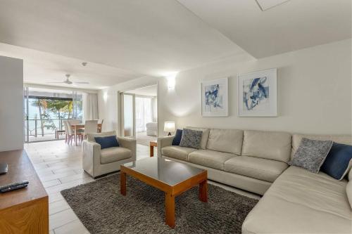 ein Wohnzimmer mit einem Sofa und einem Tisch in der Unterkunft Aspen - Beachfront Bliss at The Drift in Palm Cove