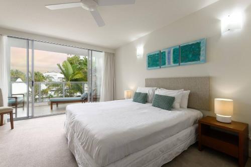 um quarto com uma grande cama branca e uma varanda em Aspen - Beachfront Bliss at The Drift em Palm Cove