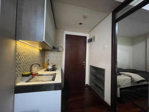 a small kitchen with a sink and a bed at Cozy Apartment 2 bedroom Gateway pasteur Bandung in Bandung