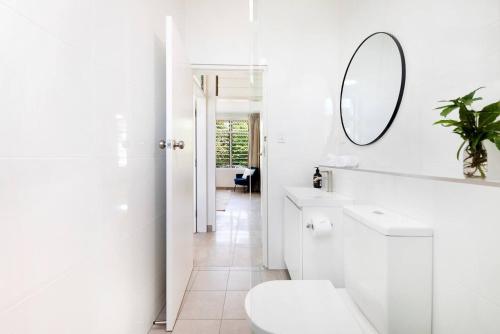 a white bathroom with a toilet and a mirror at 'The Botanica' A Triple-apartment Residence in Nightcliff in Darwin