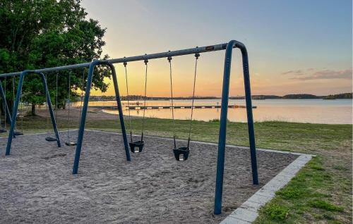 an empty swing set on the beach with the sunset at Nice Home In Timmernabben in Timmernabben