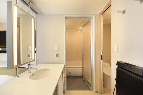 uma casa de banho branca com um lavatório e um chuveiro em Richmond Hotel Premier Asakusa International em Tóquio