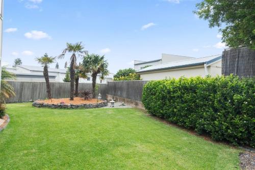 a yard with palm trees and a fence at 'Pineview Escape' Generous Comfort for Families in Shellharbour