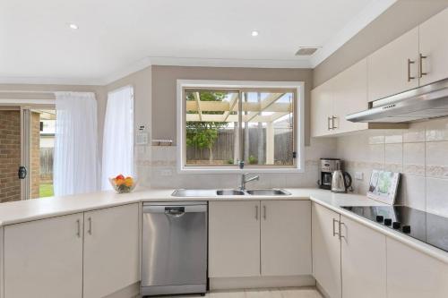 a white kitchen with a sink and a window at 'Pineview Escape' Generous Comfort for Families in Shellharbour