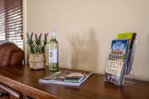 a bottle of wine on a table with a book and a magazine at Nora's Place - Explore Mudgee's Best Wineries in Mudgee