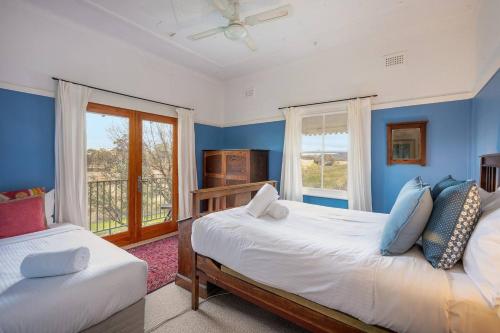 a bedroom with two beds with blue walls and a window at Reset your Senses in Meroo at Lone Pine Farmhouse in Windeyer