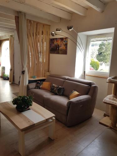 a living room with a brown couch and a table at "Chez Naty" chambres d'hôtes au Pays-Basque in Chéraute