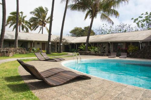 a pool with two lounge chairs next to a house at Hotel Hotu Matua in Hanga Roa