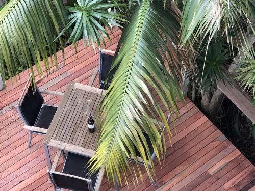 a wooden table and chairs on a deck with a palm tree at The Eagles Nest in Kiama