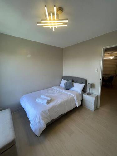 Un dormitorio con una gran cama blanca y una lámpara de araña. en Modern Oasis: Pool + Netflix, en Manila