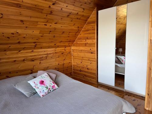 a bedroom with a bed with a wooden wall at Wakacyjny Hartowiec - dom nad brzegiem jeziora in Grodziczno