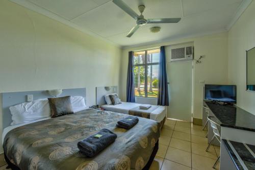 - une chambre avec un grand lit et une télévision dans l'établissement Riverview Tourist Village, à Katherine