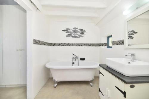 a white bathroom with a tub and a sink at Pebbles In Langezandt, Struisbaai in Struisbaai