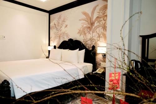1 dormitorio con 1 cama con sábanas blancas y papel pintado en Nicecy Saigon Hotel, en Ho Chi Minh