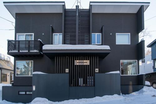 a black house with snow on the ground at Shirokuma Chalets in Kutchan