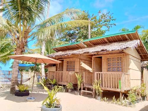 愛妮島的住宿－Kubo Inn & Beach Camp，海滩上的房子,有遮阳伞和棕榈树