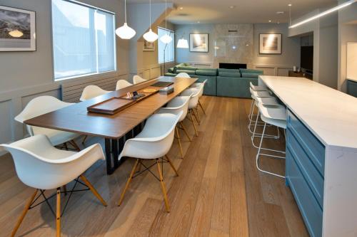 a dining room with a long table and white chairs at Shirokuma Chalets in Kutchan