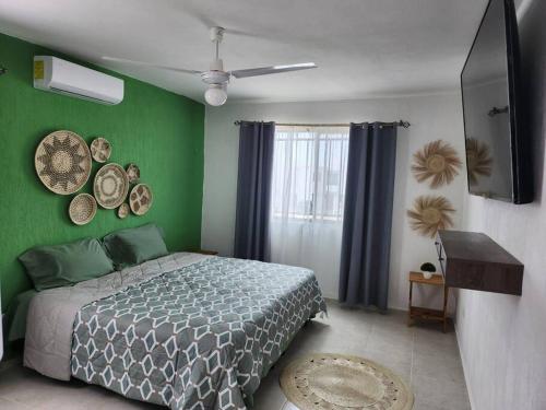 1 dormitorio con cama y pared verde en Casa Balam, en Los Heroes, con alberca, en Mérida