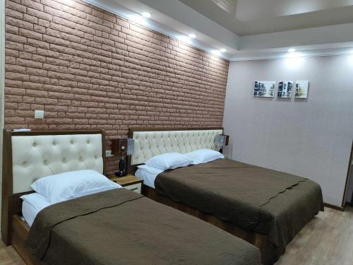 a bedroom with two beds and a brick wall at Tsereteli Inn in Kutaisi