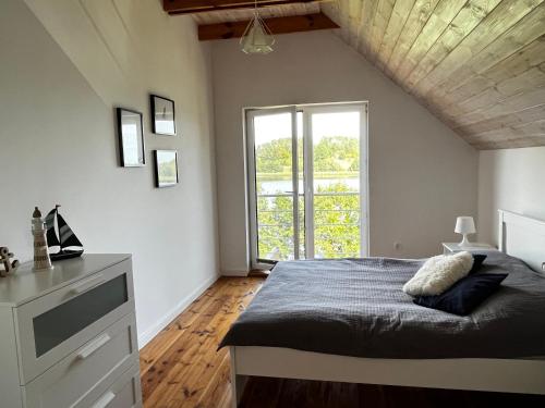a bedroom with a bed and a large window at Wakacyjny Hartowiec 2 in Grodziczno