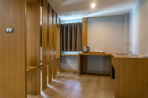 a kitchen with wooden cabinets and a sink in a room at Buritel Hotel in Buriram