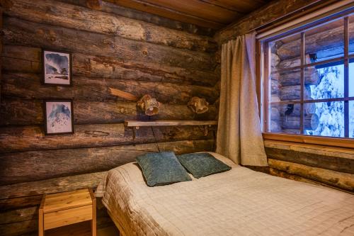 ein Schlafzimmer mit einem Bett in einem Blockhaus in der Unterkunft Kuusirinne 2B -A cozy cabin near the slopes of Ruka in Ruka