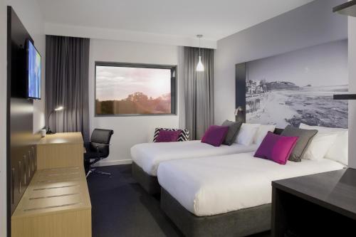 a hotel room with two beds and a desk at Mercure Newcastle Airport in Newcastle