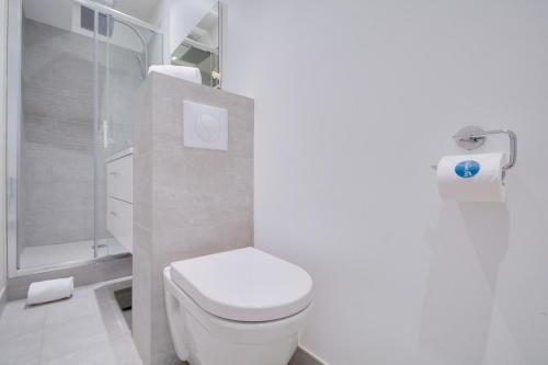a white bathroom with a toilet and a shower at Sweet Inn - Amiral de Coligny in Paris